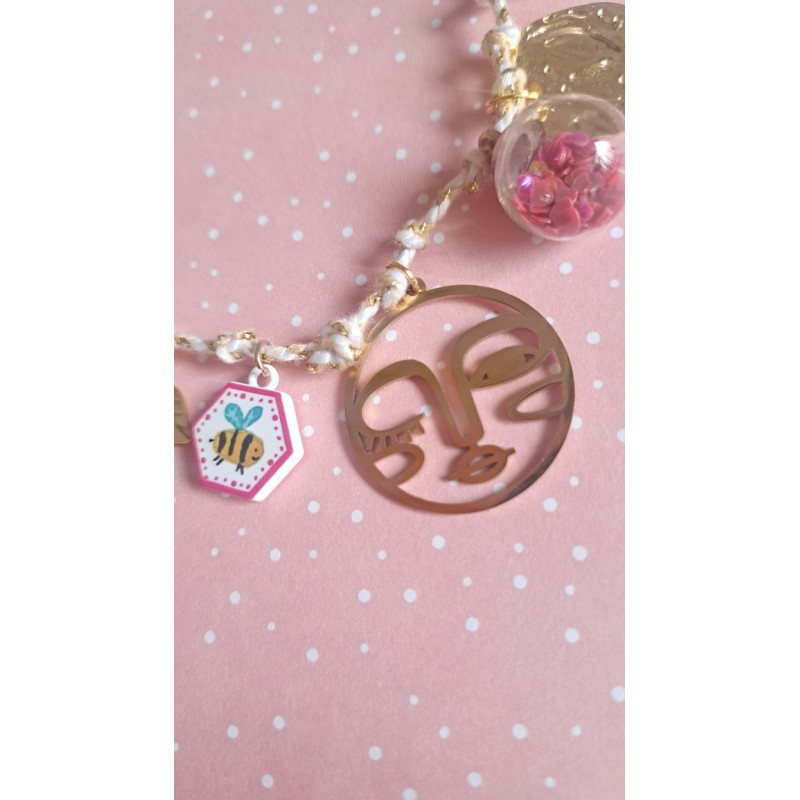 Détail collier style bohème avec breloques dorées, cordon blanc et breloques en verre